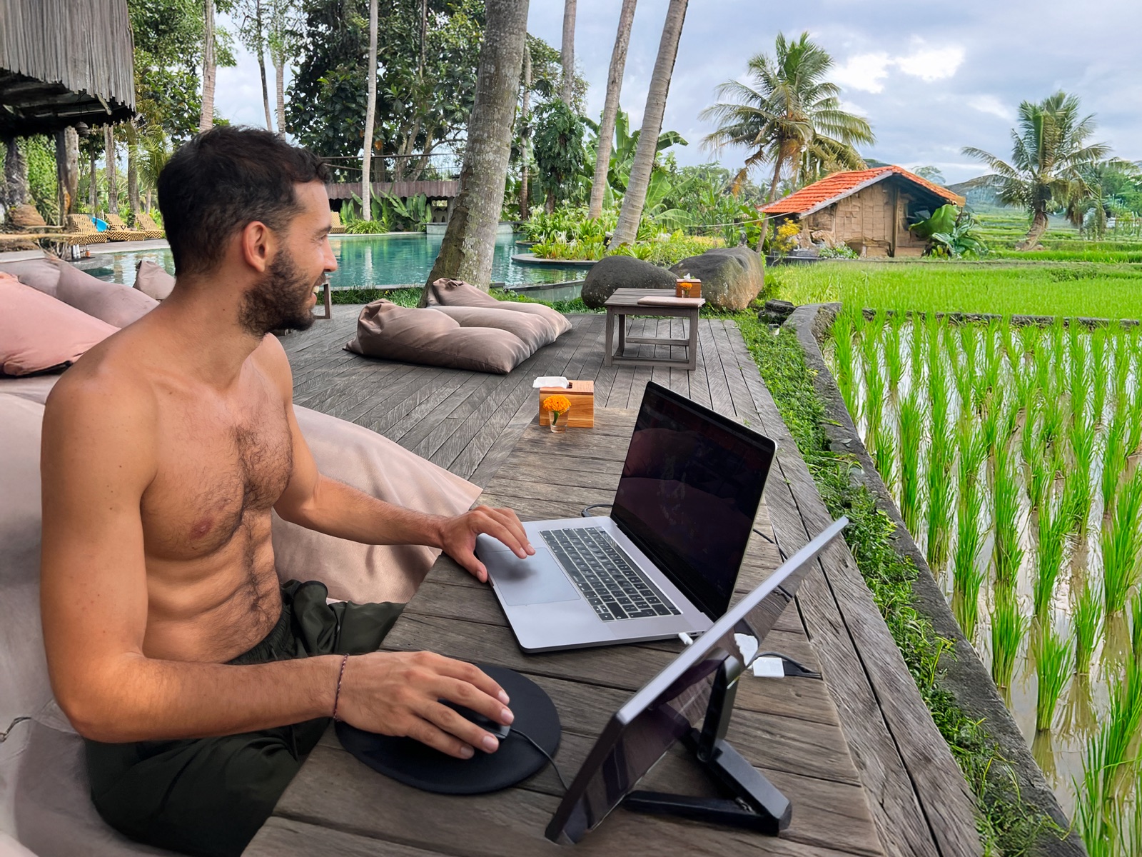 Filippo working remotely from a poolside deck overlooking rice fields in Bali