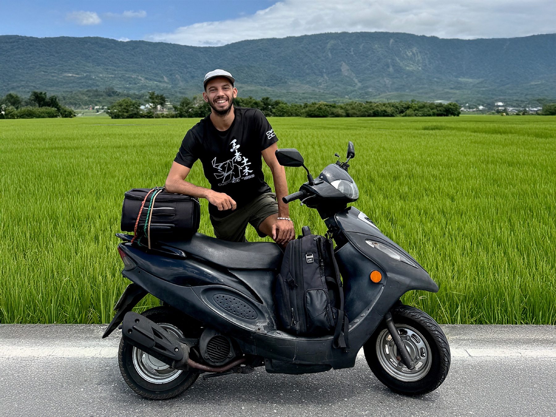 Filippo with his loaded scooter beside a rice field, Taiwan
